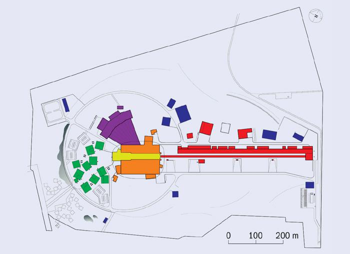 Schéma tříštivého zdroje neutronů ESS. Červeně jsou označeny budovy ukrývající urychlovač, žluté jsou místa ukrývající terč, oranžové a fialové stavby, ve kterých je experimentální zařízení, zelené jsou kanceláře a laboratoře, modré servisní budovy. (Zdroj ESS).