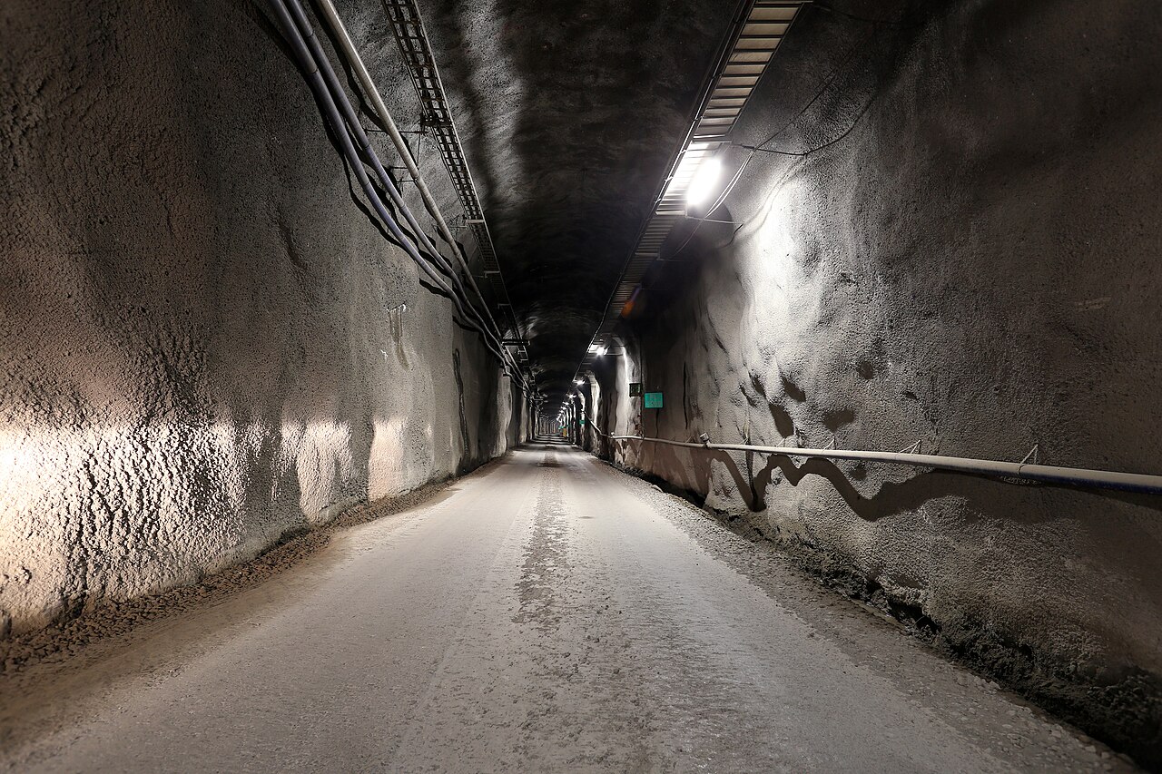 Obrázek přístupového tunelu hlubinného úložiště Onkalo ve Finsku zobrazující betonem vyztuženou podzemní chodbu vedoucí do skalního masivu
